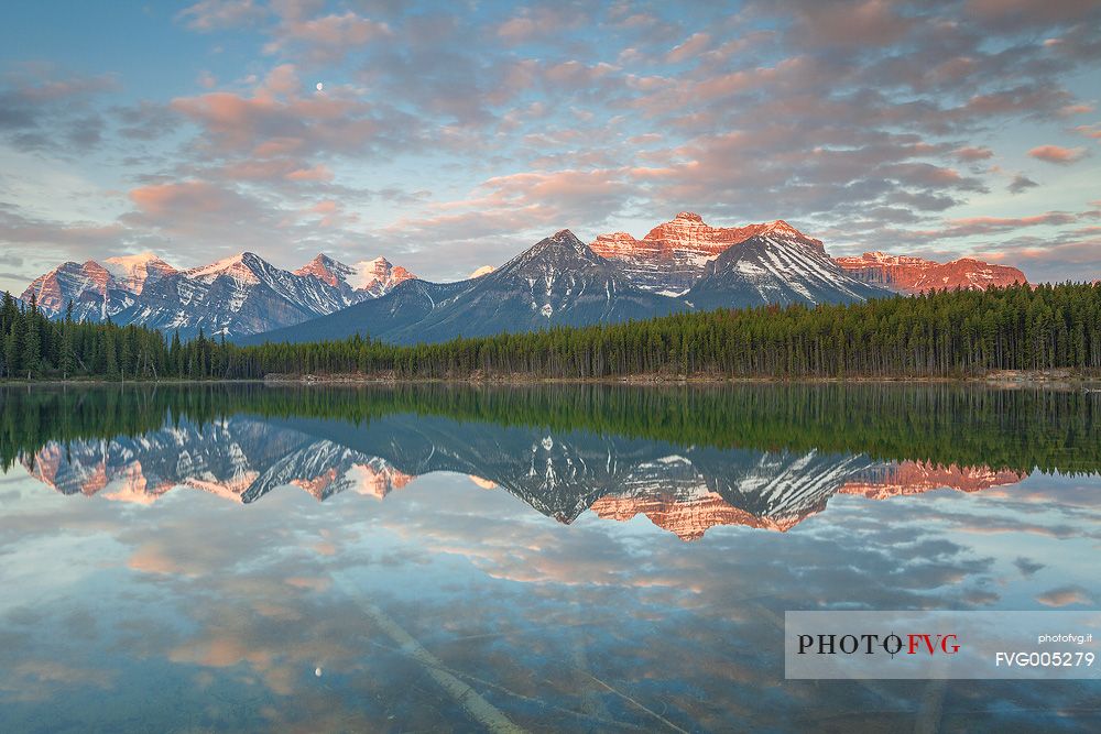 Moon is reflected at Herbert Lake during a colorful sunrise