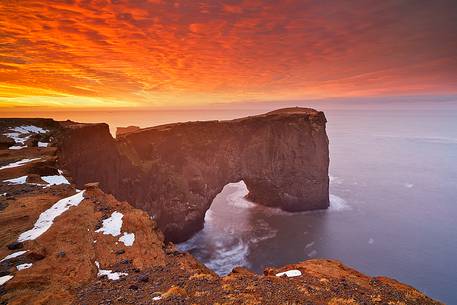 A very colourful sunrise makes the sky inflamed, on the coast nearby Vik.