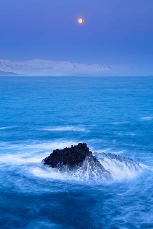 The rising moon frames a seascape whose shades are wintry