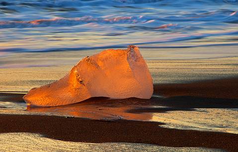 A big block of stranded ice
on the volcanic beach of Jokulsarlon becomes a spectator to a special sunrise