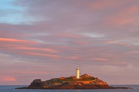 Sunrise colours and rainbow over Godrevy Lighthouse