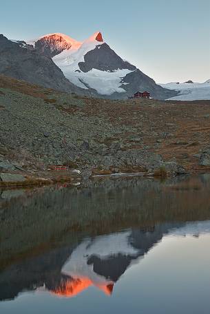 Fluhalp shelter is surrounded by amazing mountains, everything is reflected into the sharp surface of Stellisee Lake