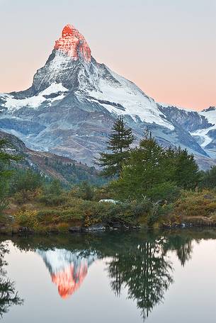 The first light of dawn strikes the top of the Matterhorn which in turn is reflected in the waters of Grindjisee