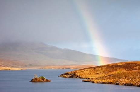 While Old Man of Storr is hiding behind the clouds a beautiful rainbow shows up in the landscape While Old Man of Storr is hiding behind the clouds a beautiful rainbow shows up in the landscape