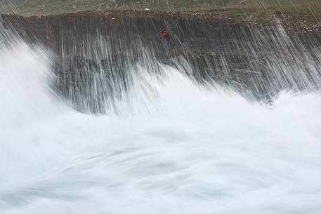 A photographer taking pictures through the wavy sea at Staffin Bay