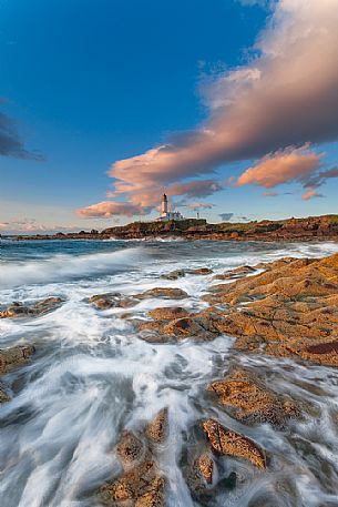 This picture of the lighthouse has been taken during the sunset, standing on the rocks This picture of the lighthouse has been taken during the sunset, standing on the rocks