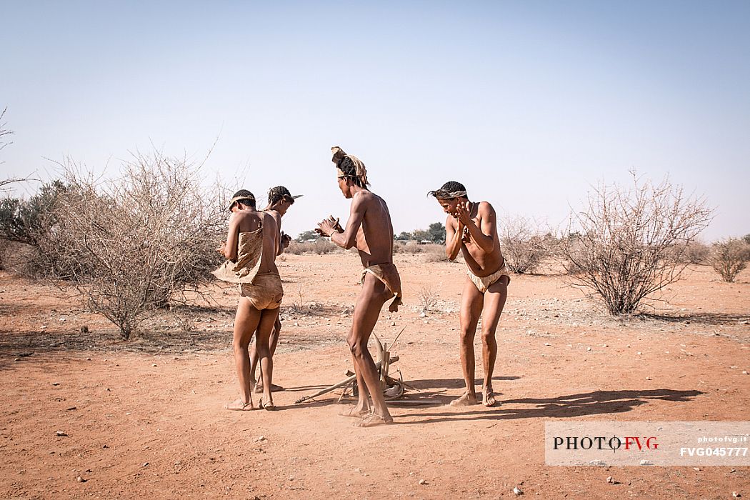 Four San men dancing in a circle during a propitiatory rite in the bush savanna of the Kalahari Desert, Namibia. Africa