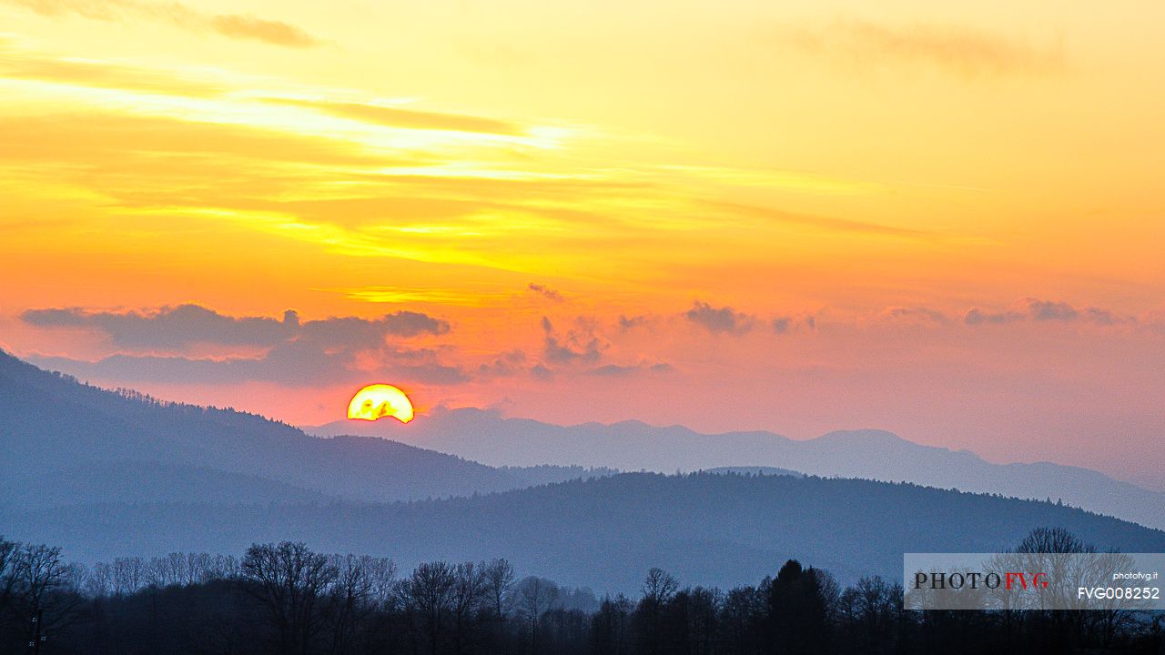 The sunset over the woods and the surrounding karst lake Cerknica