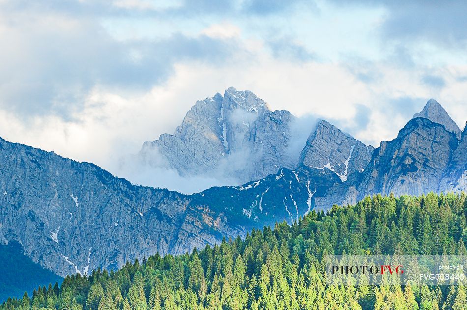 The mount Sernio emerges from the clouds and stands with majesty abiove the green woods
