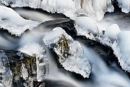 the mountain stream flowing beneath a blanket of ice