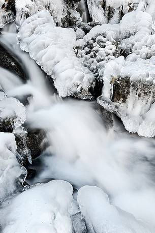the mountain stream flowing beneath a blanket of ice