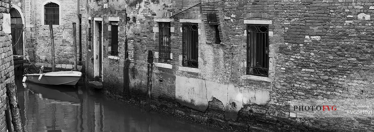 Boat moored in Venice alley canal, Italy.