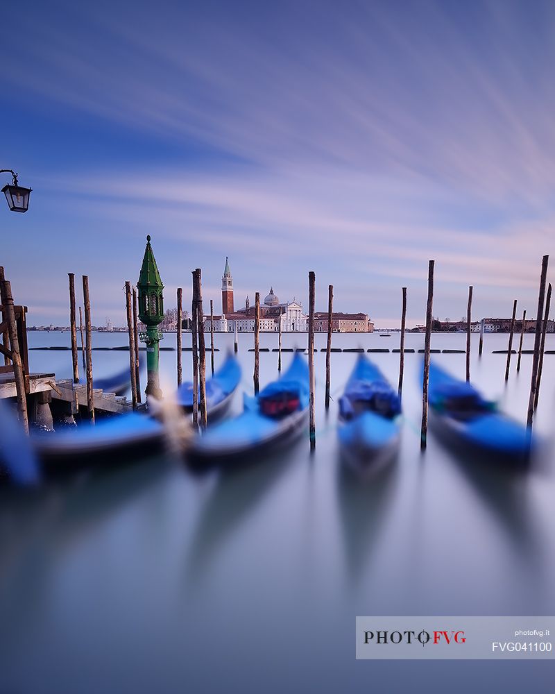 A colorful sunset in the magic mood of Venice with the traditional gondolas in the flow of time, San Giorgio Maggiore church in the background, Venice, Italy