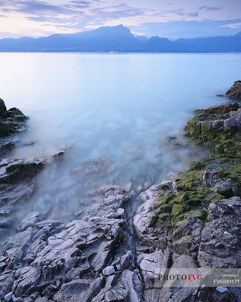 A coastal view at summer sunset from Baia delle Sirene on the eastern coast of Garda Lake, in the background the Mount Pizzocolo, Verona, Veneto, Italy, Europe