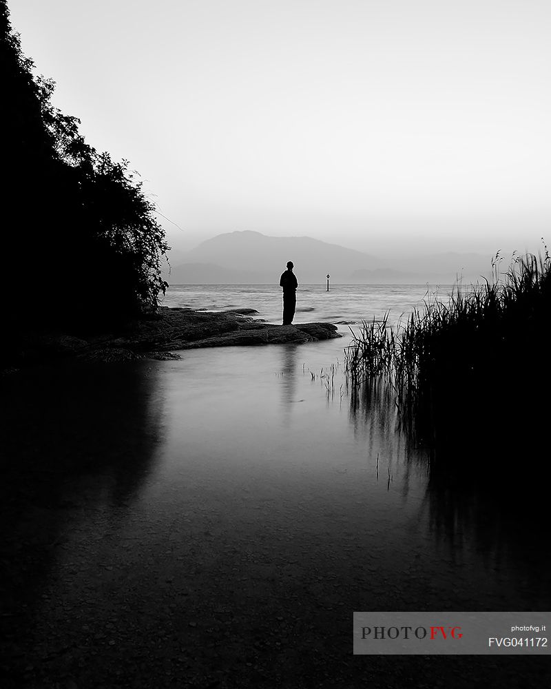 Alone people in silhouette looking the Garda lake at surrise, in the background the Mount Baldo, Sirmoione, Garda lake, Brescia, Lombary, Italy, Europe