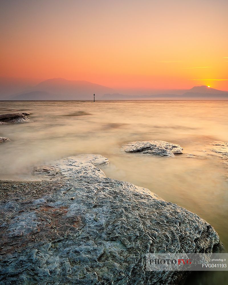 Garda lake at sunrise from Sirmione coast, in the background the Mount Baldo and the Mount Pastello, Brescia, Lombardy, Italy, Europe