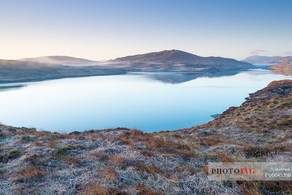 Dawn over frost covered meadows looking out over the waters of Loch Rog Beag near Giosla in the Outer Hebrides on the Isle of Harris, Scotland.