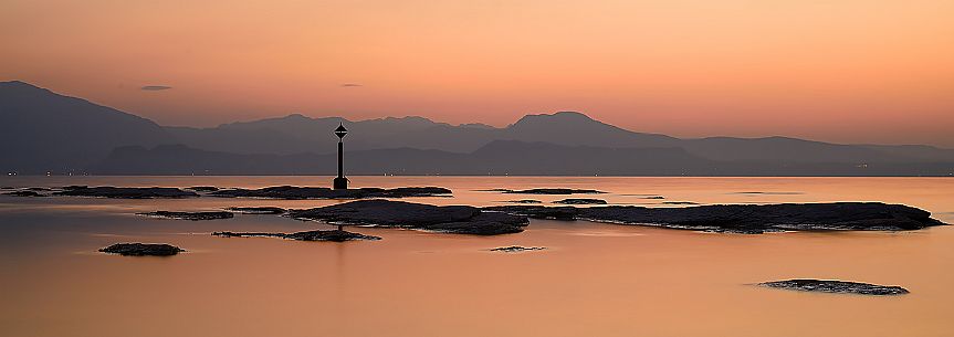 Garda lake form Sirmione village at sunset, in the background the silhouettes of Mount Baldo and Mount Pastello, Brescia, Lombardy, Italy, Europe Garda lake form Sirmione village at sunset, in the background the silhouettes of Mount Baldo and Mount Pastello, Brescia, Lombardy, Italy, Europe