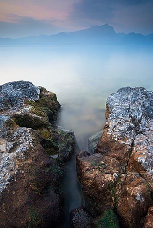 A coastal view at summer sunset from Baia delle Sirene on the eastern coast of Garda Lake, in the background the Mount Pizzocolo, Verona, Veneto, Italy, Europe