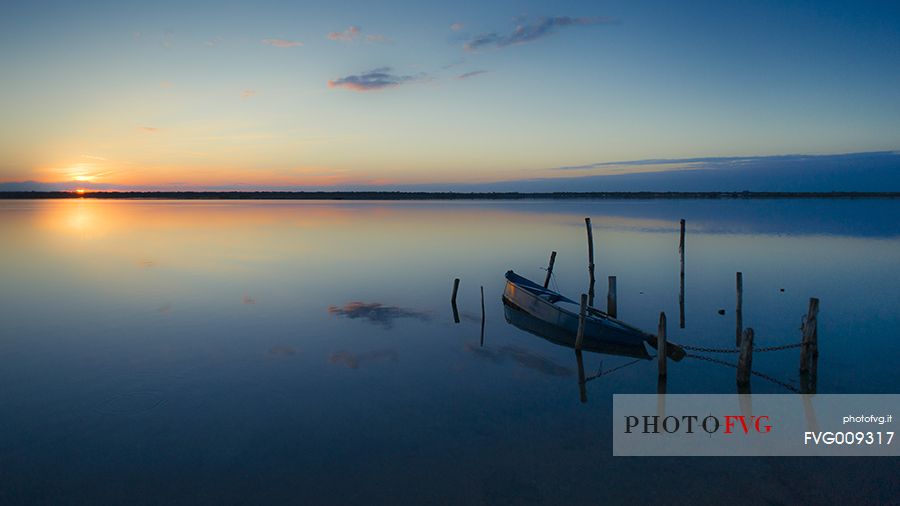 Sunset on salt lake in Ravenna whit pier, boat and fishing huts