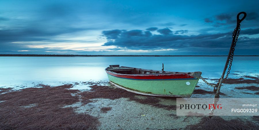 Sunset on salt lake in Ravenna whit pier, boat and fishing huts