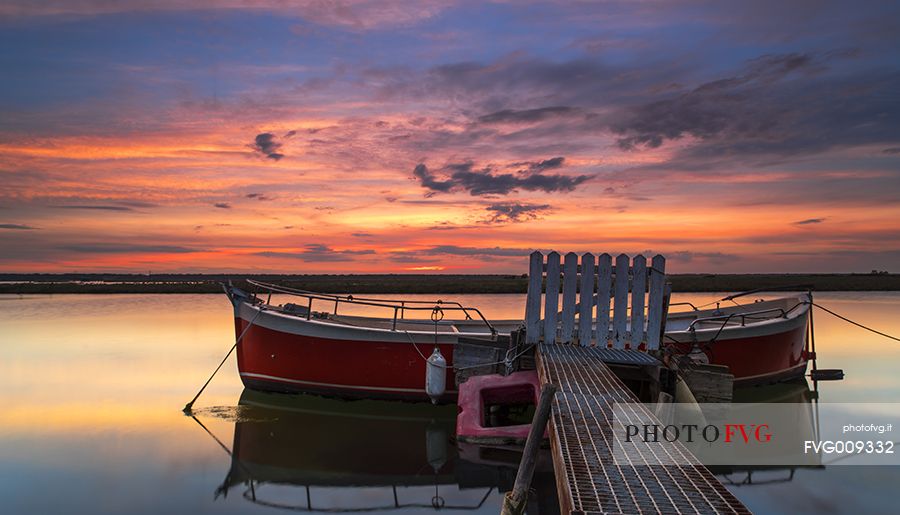 Sunset on salt lake in Ravenna whit pier, boat and fishing huts