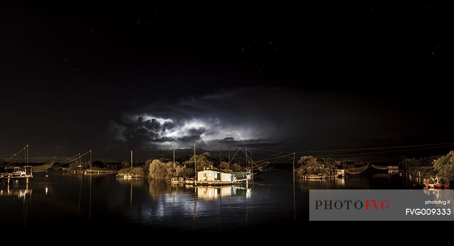 night bolt on salt lake in Ravenna whit pier, boat and fishing huts