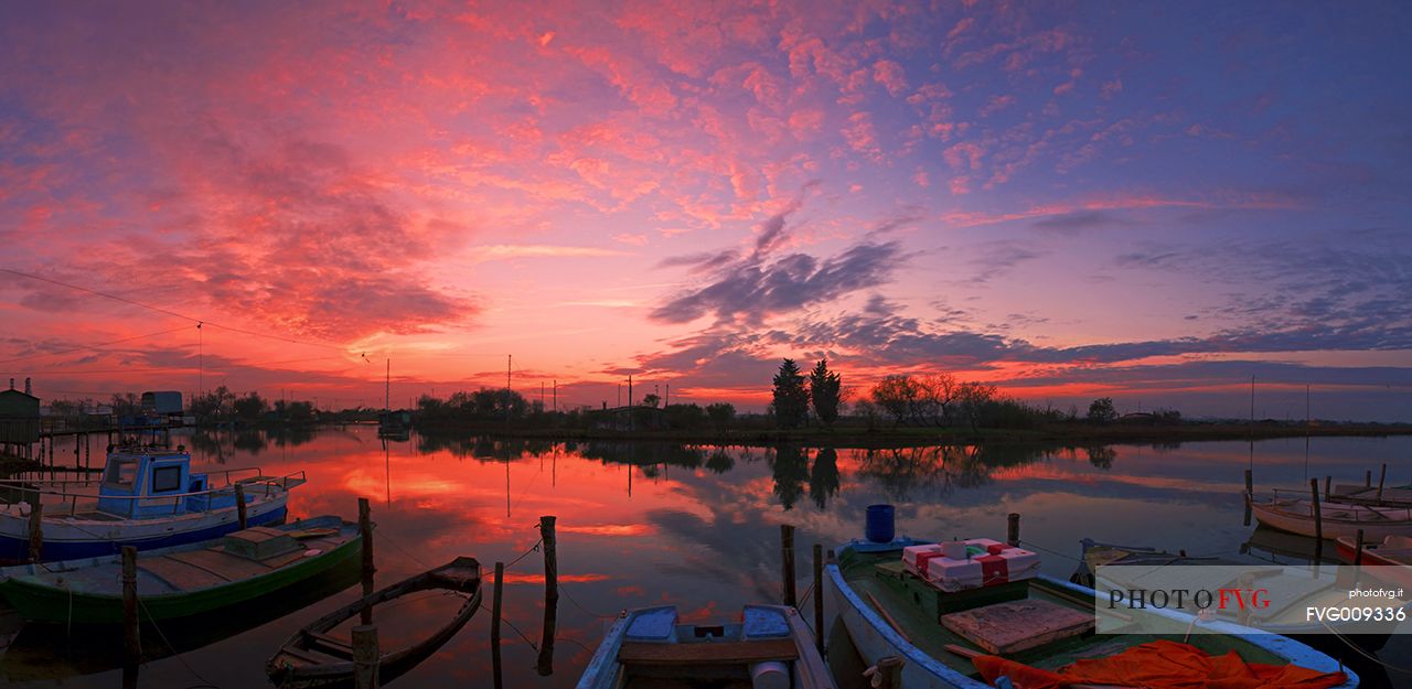 Sunset on salt lake in Ravenna whit pier, boat and fishing huts