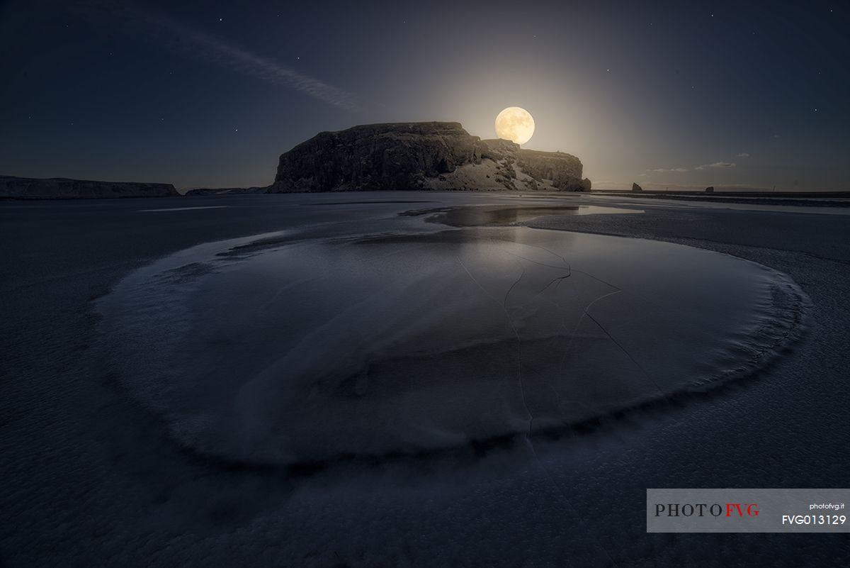 Full moon over icelandic beach in south iceland