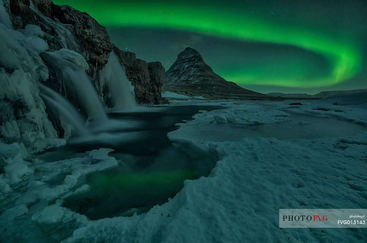 Northern lights over Kirkjufell mountain with water falls at winter, Iceland