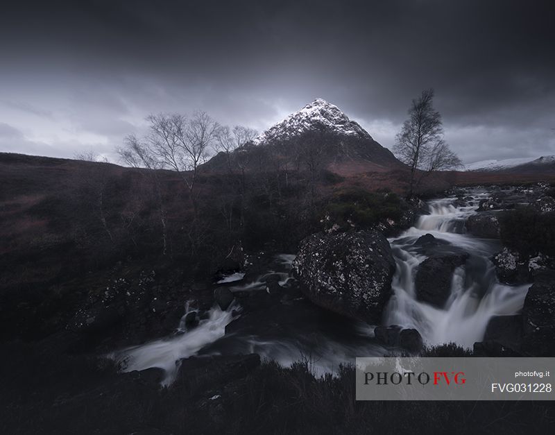 Waterfall and Buachaille Etive Mr peak in a stormy sky, Glencoe, Scotland, UK