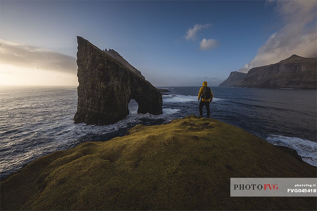 Hiker at Drangarni sea stack in Vagar island, Faeroe islands, Denmark, Europe