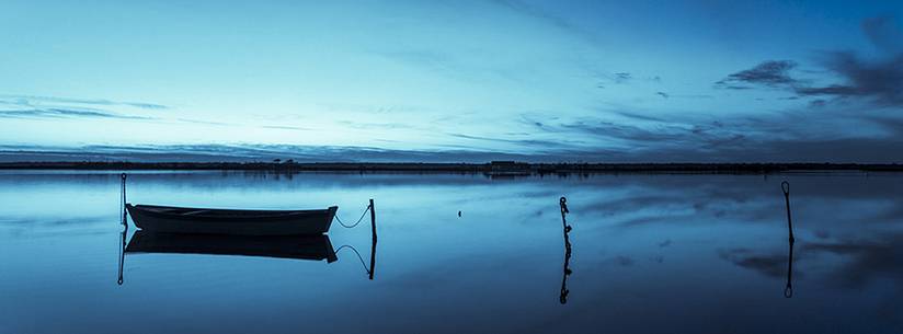 Sunset on salt lake in Ravenna whit pier, boat and fishing huts