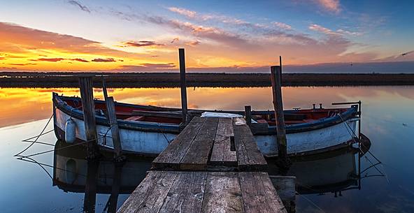 Sunset on salt lake in Ravenna whit pier, boat and fishing huts