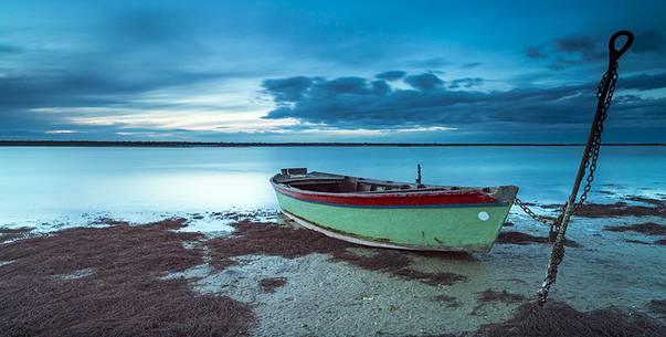 Sunset on salt lake in Ravenna whit pier, boat and fishing huts