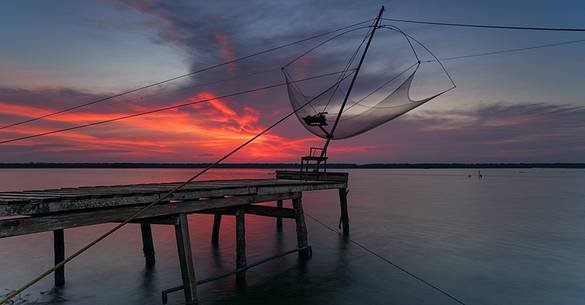 Sunset on salt lake in Ravenna whit pier, boat and fishing huts