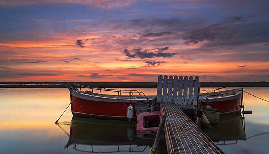 Sunset on salt lake in Ravenna whit pier, boat and fishing huts