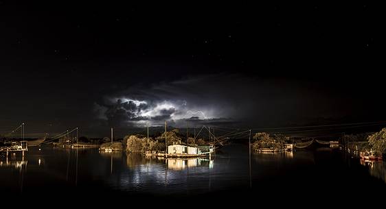 night bolt on salt lake in Ravenna whit pier, boat and fishing huts night bolt on salt lake in Ravenna whit pier, boat and fishing huts