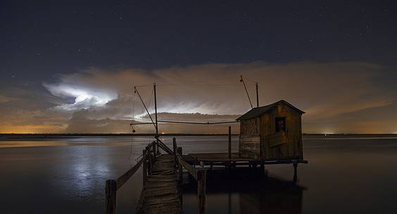 night bolt on salt lake in Ravenna whit pier, boat and fishing huts night bolt on salt lake in Ravenna whit pier, boat and fishing huts
