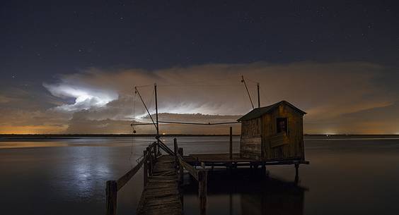 night bolt on salt lake in Ravenna whit pier, boat and fishing huts