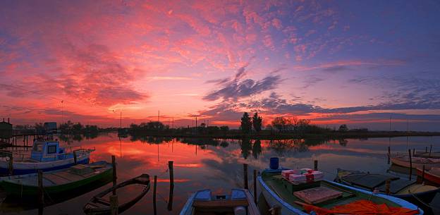 Sunset on salt lake in Ravenna whit pier, boat and fishing huts