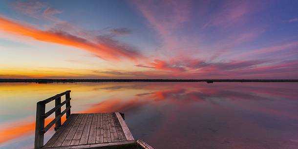 Sunset on salt lake in Ravenna whit pier, boat and fishing huts