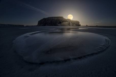 Full moon over icelandic beach in south iceland