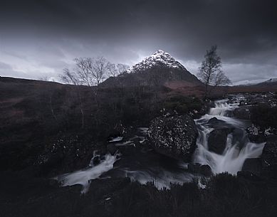 Waterfall and Buachaille Etive Mr peak in a stormy sky, Glencoe, Scotland, UK