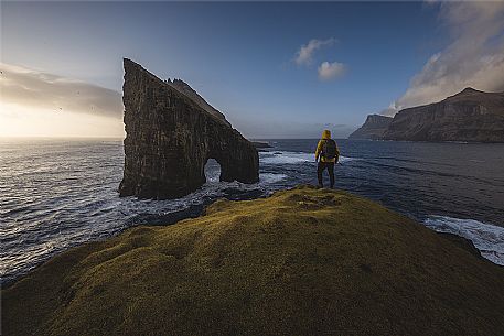 Hiker at Drangarni sea stack in Vagar island, Faeroe islands, Denmark, Europe