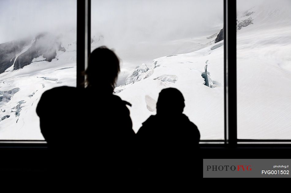 Mother and son inside the Sphinx Observatory on top of the Jungfraujoch, admiring the Aletsch glacier, the largest in Europe, Bernese alps, Switzerland, Europe