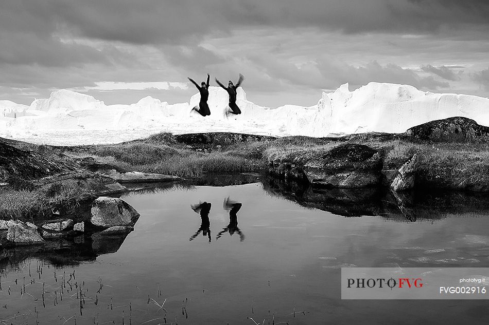 Hiking and action near a small pond; in the background icebergs in Kangerlua  Fjord