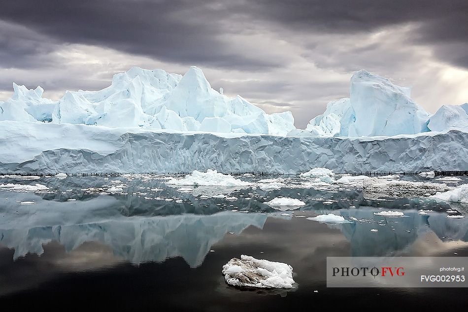 Reflections on sea of blue icebergs in Disko Bay