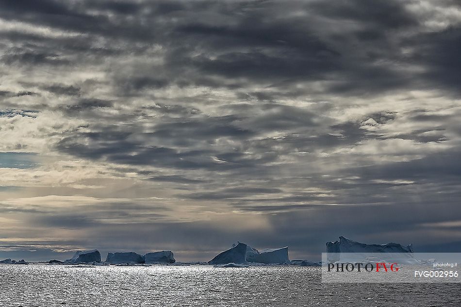 Dark clouds above blue icebergs in Disko Bay