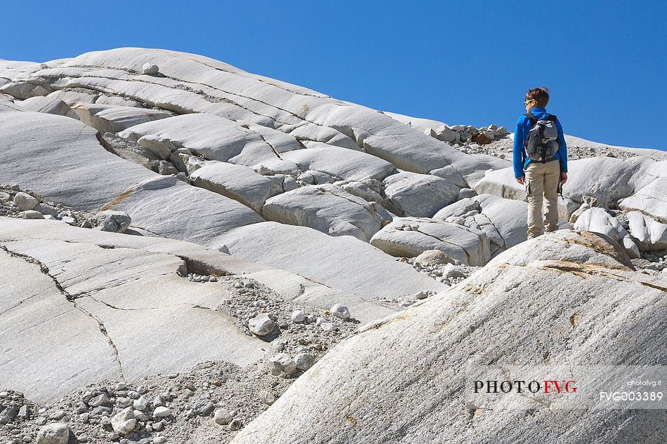 Boy walks in the moraine of the Rhone glacier, Furka pass, Valais, Switzerland, Europe